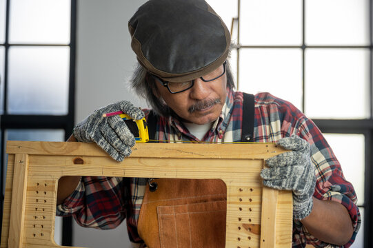 Carpenter working on wood craft using saw and ruler tools for hand crafting at workshop to produce construction material or wooden furniture . DIY maker and carpentry work concept.