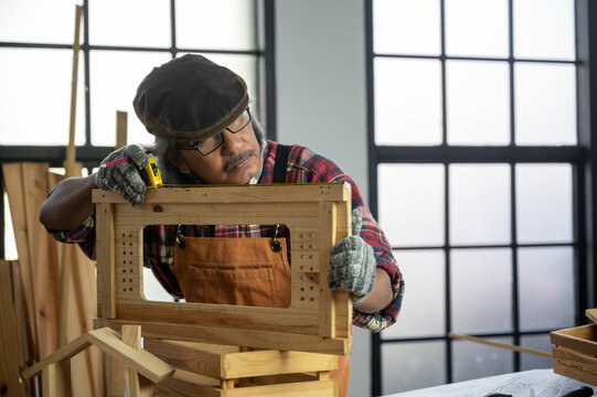 Carpenter working on wood craft using saw and ruler tools for hand crafting at workshop to produce construction material or wooden furniture . DIY maker and carpentry work concept. - Powered by Adobe