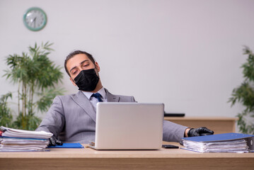 Young male employee in the office during pandemic disease