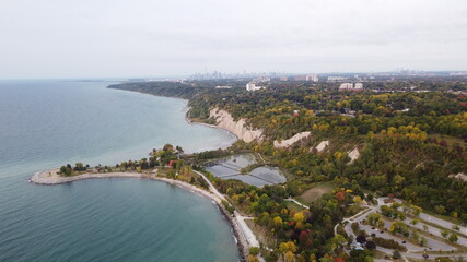 Fototapeta na wymiar Aerial Panoramic Landscape Image of a Coastline in Toronto with beautiful park and skyline and nature view during fall with autumn colours during dawn