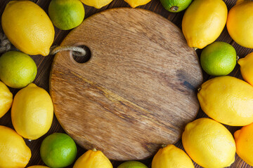 Scattered lemons with limes on wooden and cutting board background, flat lay.