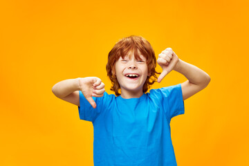 Joyful redhead boy with open mouth showing thumbs down blue t-shirt  © SHOTPRIME STUDIO