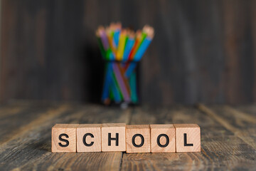 Back to school concept with wooden cubes, pencils in holder on wooden background side view.