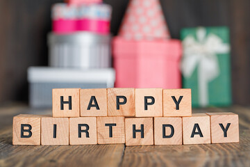 Birthday concept with gift boxes, wooden cubes on wooden background side view.