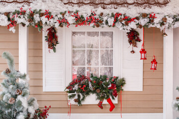 Fototapeta na wymiar Christmas decorated house and yard. Studio decoration in New Year style. Snow covered courtyard of a wooden house or cottage with red decore accents. Backdrop for photographer