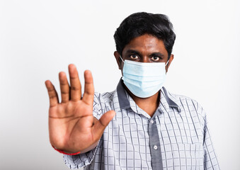 Closeup Asian handsome black man wearing surgical hygienic protective cloth face mask against coronavirus and raising hand stop sign, studio shot isolated white background, COVID-19 medical concept