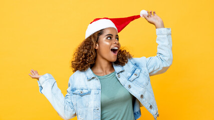 Fun surprised happy African American woman wearing Christmas hat on yellow isolated background