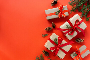 Holiday gift boxes with ribbon, fir and cones on a red background. Flat lay for christmas and new year, space for text