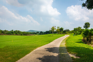 The road way for golf cart and golfer  in golf course with green grass ,green trees blue sky white clouds background