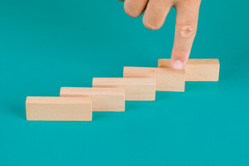 Business and risk management concept on turquoise background high angle view. finger showing wooden block.