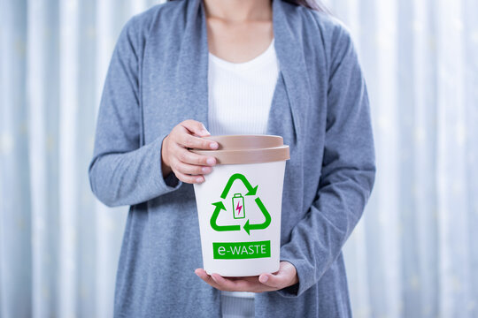 Woman holding electronic waste bin, E-waste concept.
