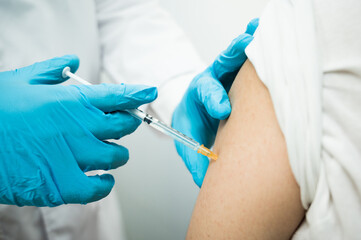 Doctor injecting vaccine covid-19 to young man. Vaccination concept.