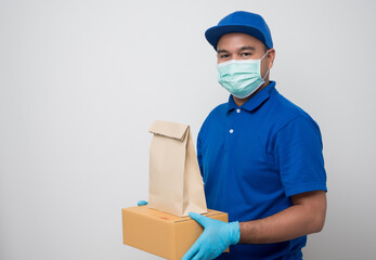 Fototapeta na wymiar Happy asian delivery man in blue uniform wearing protection mask and medical gloves giving the paper bag and parcel box cardboard to customer on isolated white background. Safety deliver concept..