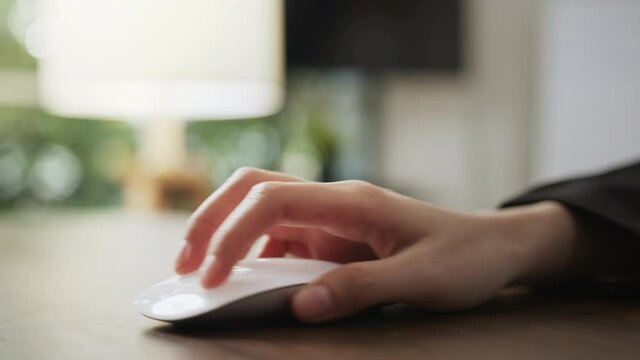 Hand using white mouse button on office desk.