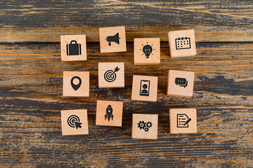 Business concept with icons on wooden cubes on wooden background flat lay.