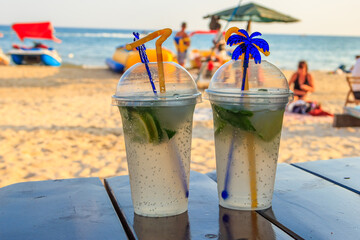 Two fresh mojito cocktails on a table on a background of tropical beach