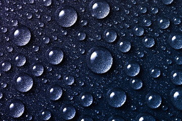 Dim background with water drops close-up, round droplets on a dark grunge background