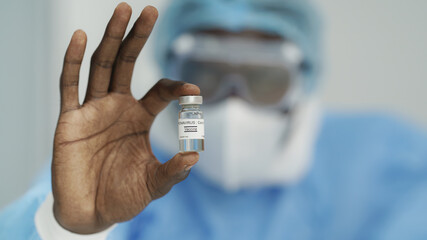 closeup of coronavirus covid-19 vaccine in bottle in hand of african american doctor
