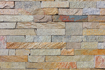 The texture of the old wall lined with shiny rough sandstone tiles.