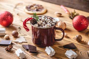A cup of aromatic tasty hot chocolate with marshmallows decorated with red candy on a wooden table...