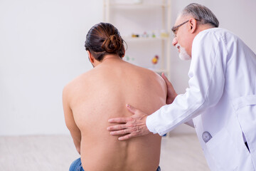 Young back injured man visiting experienced male doctor