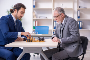 Naklejka na ściany i meble Two businessmen playing chess in the office