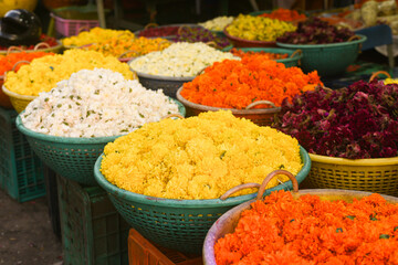 Flower shop in the street during Onam festival in Kerala, India. Baskets full of colorful flowers, garland for sale in shop on a street. Many yellow garland of marigold, Jasmine displayed.