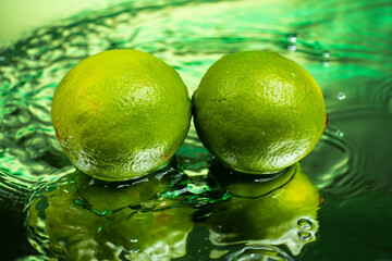 Fototapeta na wymiar two whole limes with splashing water on gradient background