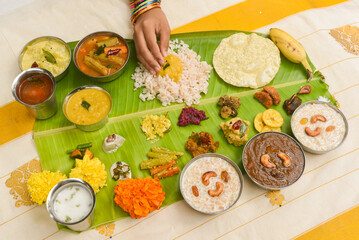 Onam sadhya, Indian women eating with hand boiled rice, served for Kerala Indian festival  with curries Sambar, Avial, Thoran, Papadum, Payasam, Banana, Yogurt or Buttermilk, banana chips