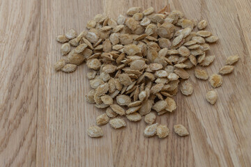 Pumpkin seeds on wooden background, close up