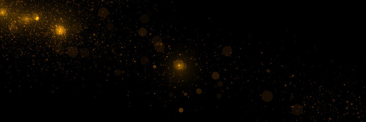 Golden particles, sparkling glitter dust on dark background.	