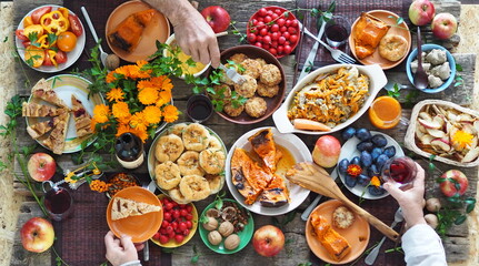 Country style. Thanksgiving table. Lots of food with red wine. The guests eat food with their hands over the set table. View from above.