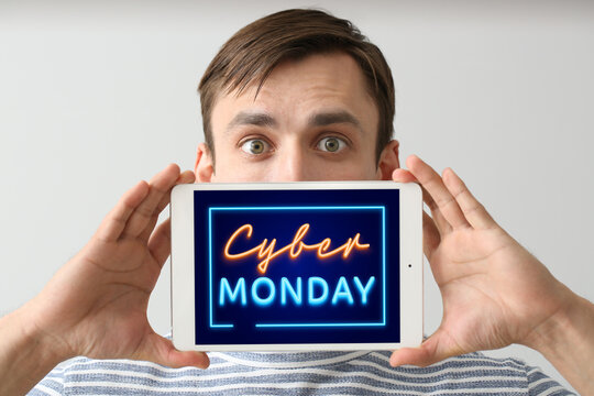 Young man with tablet computer on light background. Concept of cyber monday
