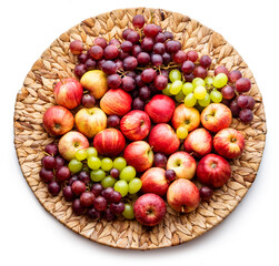 Red apples and grapes on a wicker dish. Harvest