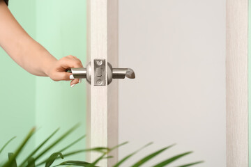 Woman opening door indoors, closeup