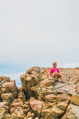 New generation will solve humanity problems. Child boy on beautiful natural composition vivid brown stone rock shabby cliff cracks high in mountains, copy space in cloud. Nature power after pandemic