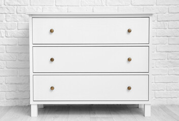 Modern chest of drawers near brick wall in room