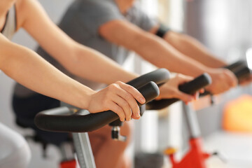 Fototapeta na wymiar Young woman training on exercising bike in gym, closeup