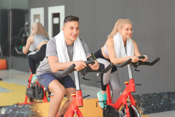 Fototapeta na wymiar Young people training on exercising bike in gym