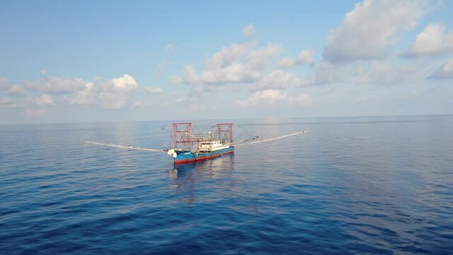 A fishing vessel catches fish in the open ocean. Aerial 4K shot.