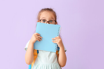 Surprised little schoolgirl with notebook on color background