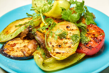 Grilled vegetables bell pepper, zucchini, tomato, mushrooms, red onion on the blue plate