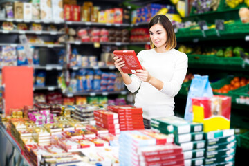 Young woman choosing delicious sweets in supermarket