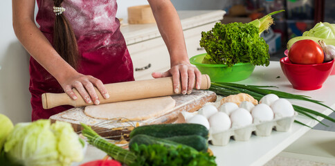 child wear cook uniform. chef girl in apron. kid cooking food in kitchen. choosing career. little helper roll dough with rolling pin. culinary and cuisine. happy childhood. fresh summer vegetables