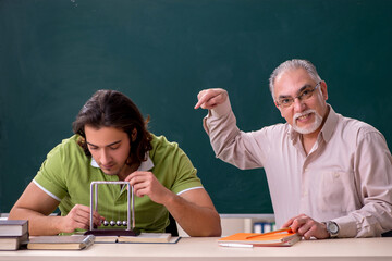 Old professor physicist and young student in the classroom
