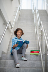 Boy sitting on city stairs with book