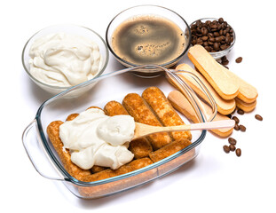 tiramisu dessert cooking - Traditional Italian Savoiardi ladyfingers Biscuits and cream in glass baking dish isolated on white with clipping path