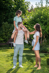 Fototapeta premium Father holding son on shoulders, his wife touching his hand, looking at them