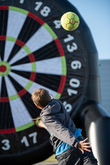 Boy throwing a soccer ball to huge dartboard
