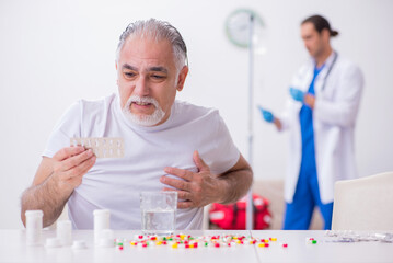 Young male doctor visiting old male patient at home